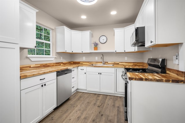 kitchen with white cabinetry, sink, stainless steel appliances, and wood counters