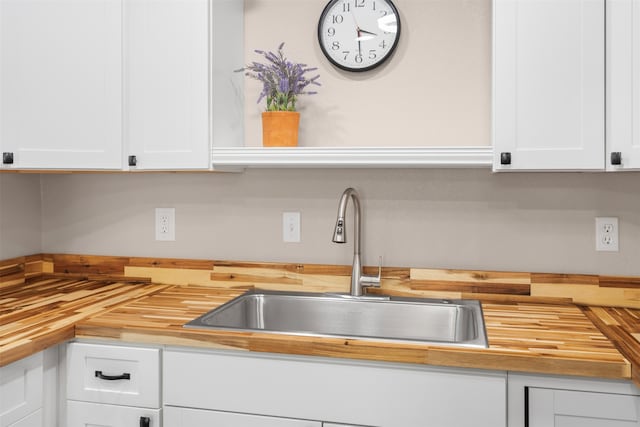 kitchen featuring wood counters, white cabinetry, and sink