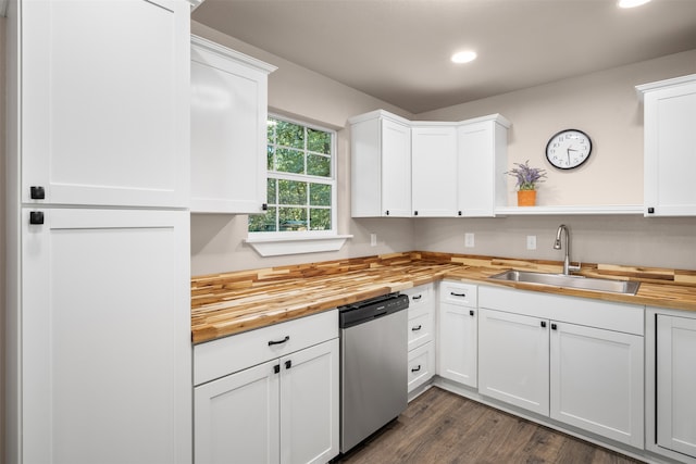 kitchen with butcher block countertops, stainless steel dishwasher, white cabinetry, and sink