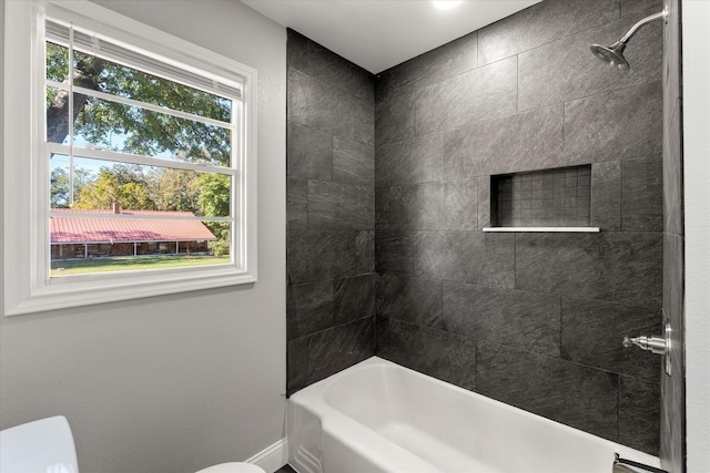 bathroom featuring toilet and tiled shower / bath