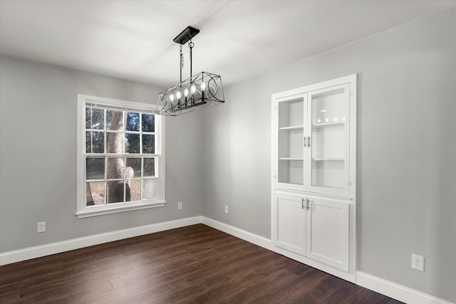 unfurnished dining area featuring a notable chandelier and dark hardwood / wood-style flooring