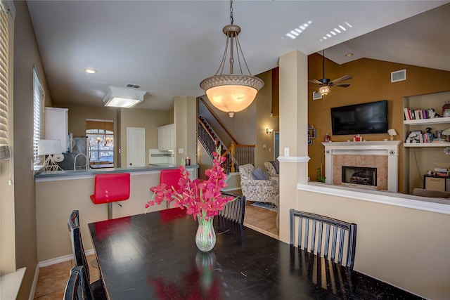 tiled dining space featuring ceiling fan, lofted ceiling, and a tiled fireplace