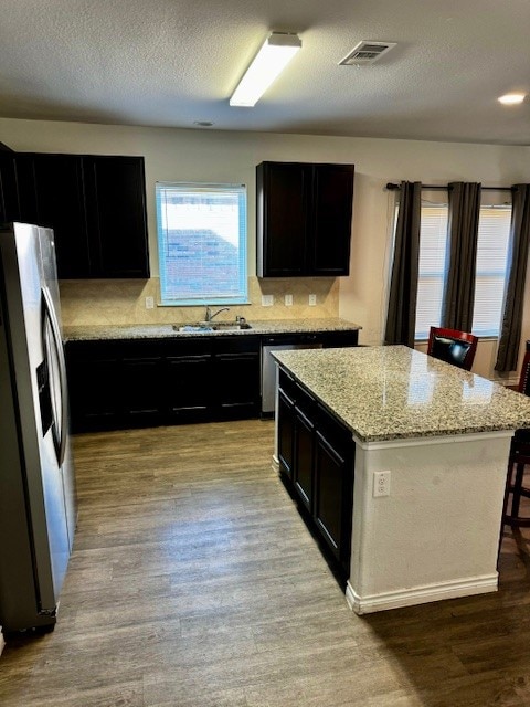 kitchen featuring stainless steel fridge with ice dispenser, a center island, light hardwood / wood-style floors, and sink