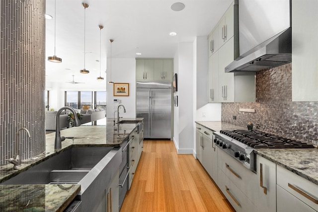 kitchen featuring decorative light fixtures, sink, light wood-type flooring, and stainless steel appliances