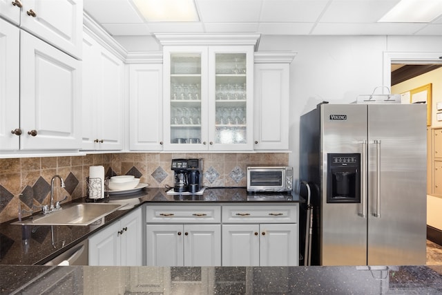 kitchen featuring white cabinets, a drop ceiling, sink, and high quality fridge