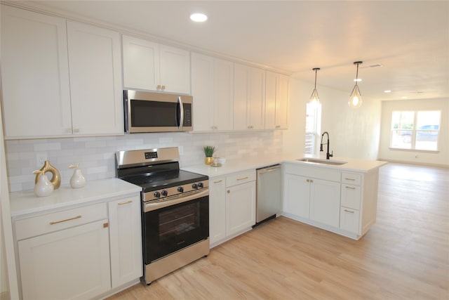 kitchen featuring white cabinetry, sink, kitchen peninsula, decorative light fixtures, and appliances with stainless steel finishes