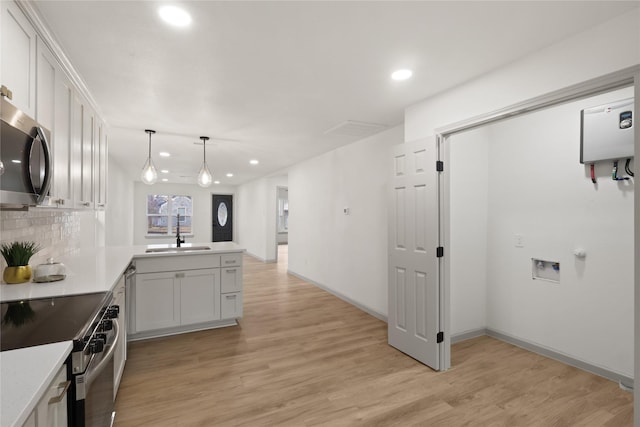 kitchen with pendant lighting, sink, white cabinets, kitchen peninsula, and stainless steel appliances