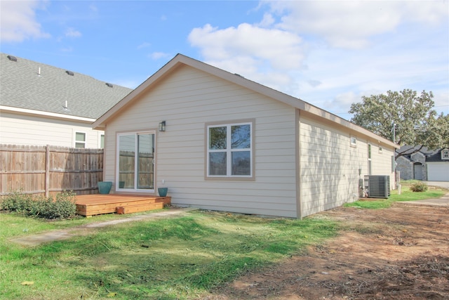 rear view of property featuring a lawn, central air condition unit, and a wooden deck