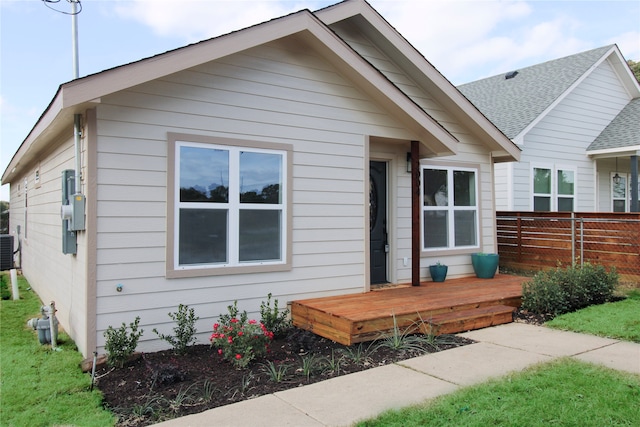 bungalow-style house featuring central AC unit and a deck