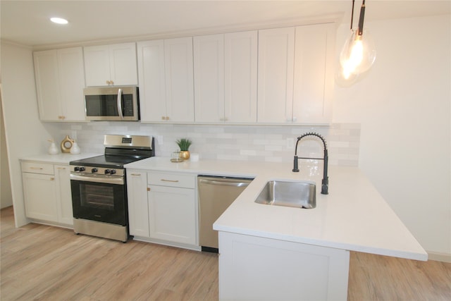 kitchen featuring kitchen peninsula, appliances with stainless steel finishes, sink, decorative light fixtures, and white cabinets