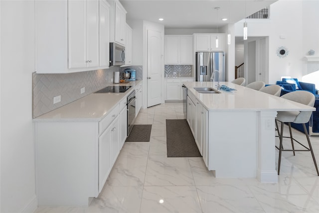 kitchen with a breakfast bar, white cabinetry, sink, a kitchen island with sink, and stainless steel appliances