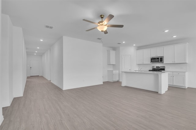 unfurnished living room with ceiling fan, sink, and light wood-type flooring