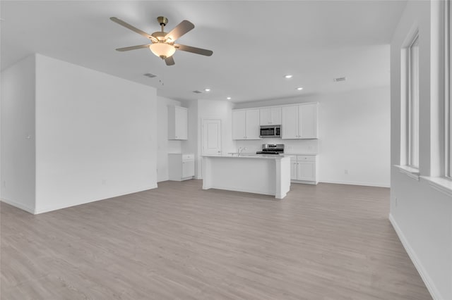 unfurnished living room with light hardwood / wood-style flooring, ceiling fan, and sink