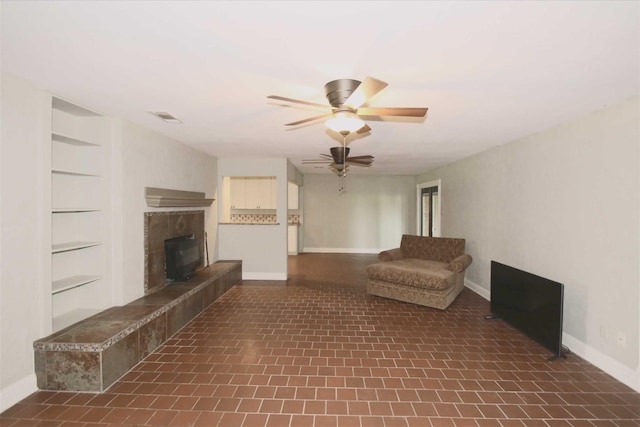 unfurnished room featuring built in shelves, dark tile patterned floors, and ceiling fan