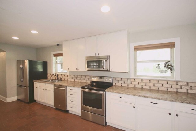 kitchen with pendant lighting, backsplash, white cabinets, and stainless steel appliances