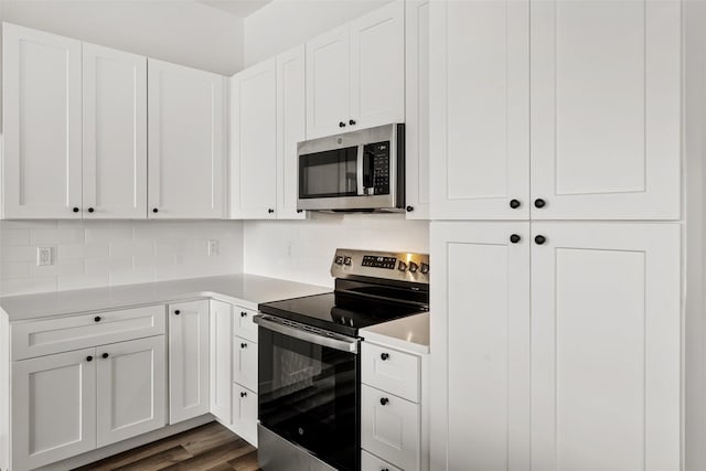 kitchen with decorative backsplash, white cabinetry, dark hardwood / wood-style flooring, and stainless steel appliances