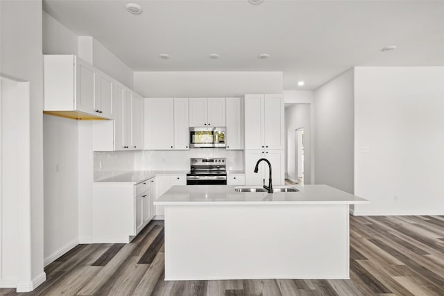 kitchen with a center island with sink, white cabinets, sink, hardwood / wood-style flooring, and appliances with stainless steel finishes