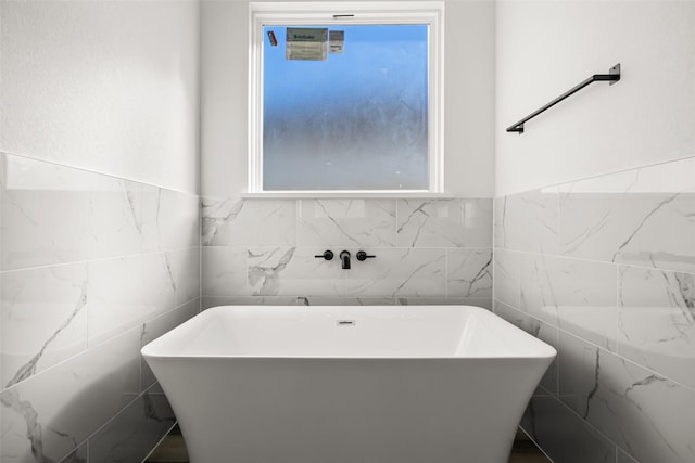 bathroom featuring a wealth of natural light, tile walls, and a bathing tub