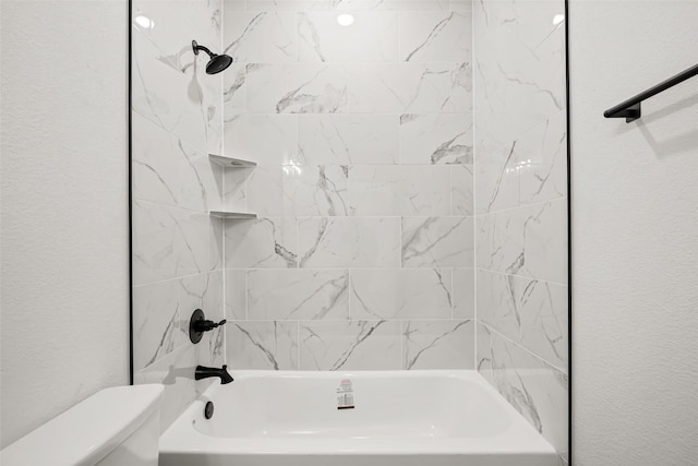 bathroom featuring toilet and tiled shower / bath