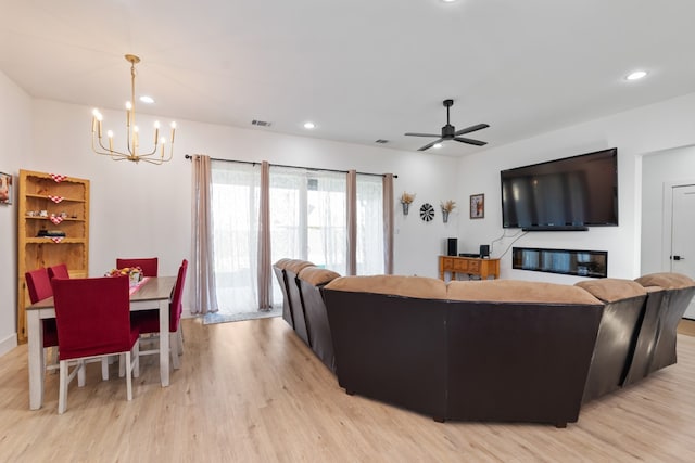 living room featuring ceiling fan with notable chandelier and light hardwood / wood-style floors