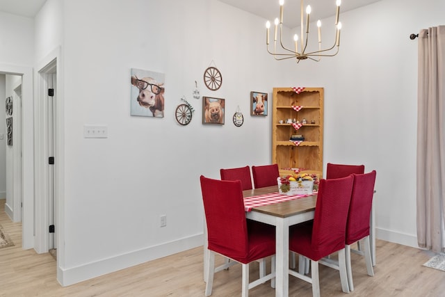 dining area with light hardwood / wood-style floors and a notable chandelier