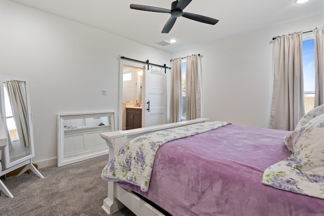 bedroom featuring a barn door, carpet flooring, connected bathroom, and ceiling fan