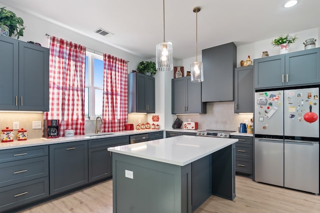 kitchen with appliances with stainless steel finishes, sink, a kitchen island, and light hardwood / wood-style flooring