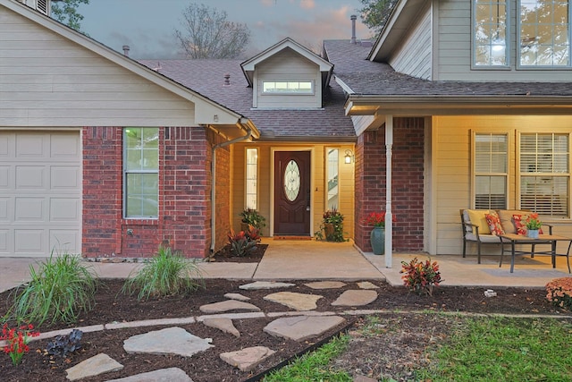 exterior entry at dusk with covered porch and a garage