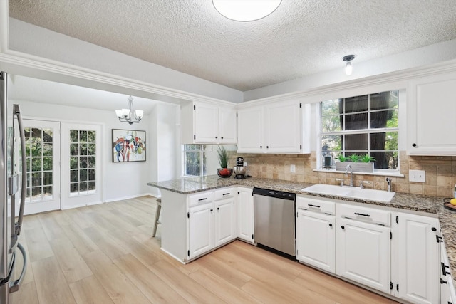 kitchen featuring white cabinetry, sink, dark stone countertops, kitchen peninsula, and stainless steel appliances