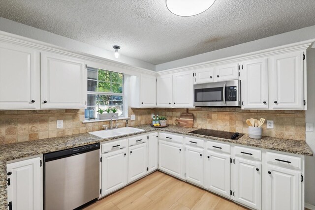 kitchen with white cabinets, light wood-type flooring, sink, and appliances with stainless steel finishes