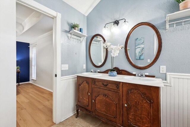 bedroom with ornamental molding, a raised ceiling, ceiling fan, light hardwood / wood-style flooring, and connected bathroom