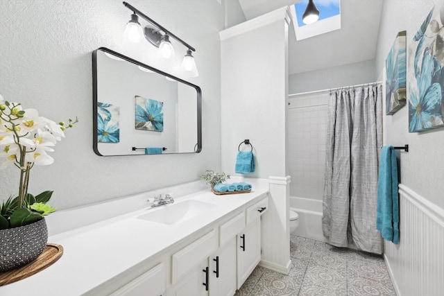 full bathroom with a skylight, vanity, shower / bath combination with curtain, tile patterned floors, and toilet