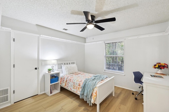 bedroom featuring ceiling fan, a textured ceiling, and light hardwood / wood-style floors