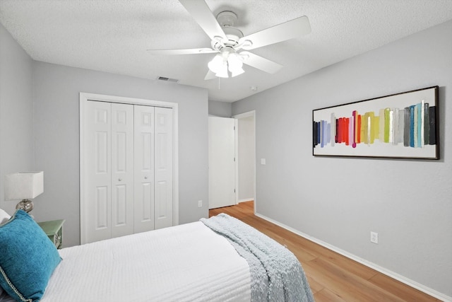 bedroom with hardwood / wood-style floors, a closet, a textured ceiling, and ceiling fan