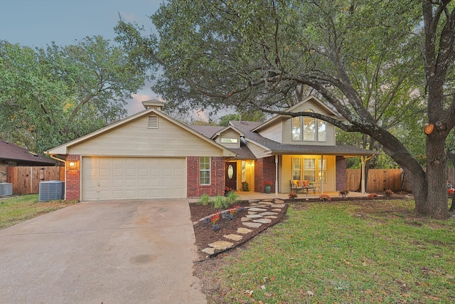 view of front of home featuring covered porch, central AC, a garage, and a lawn