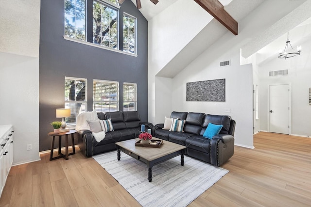 living room featuring beamed ceiling, high vaulted ceiling, an inviting chandelier, and light wood-type flooring