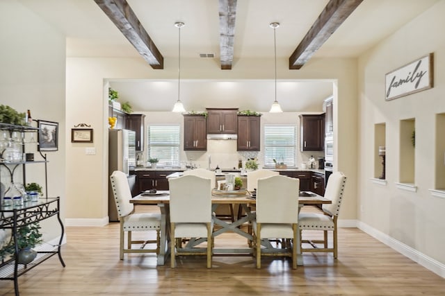 dining room featuring a wealth of natural light, beamed ceiling, and light hardwood / wood-style floors