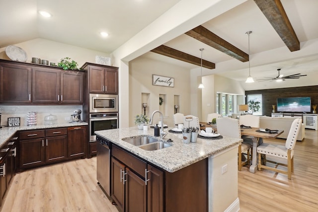 kitchen with light stone countertops, sink, stainless steel appliances, tasteful backsplash, and decorative light fixtures