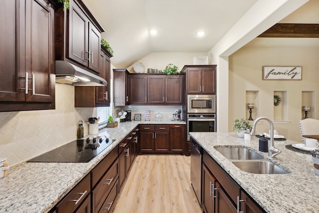 kitchen with stainless steel appliances, light stone counters, light hardwood / wood-style floors, and sink