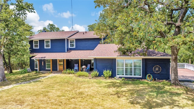 traditional home with a front lawn, covered porch, roof with shingles, and a chimney