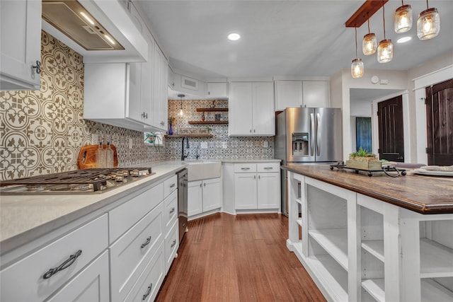 kitchen with open shelves, butcher block counters, custom range hood, appliances with stainless steel finishes, and a sink