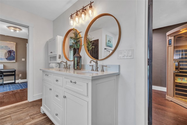 full bathroom with double vanity, wood finished floors, baseboards, and a sink