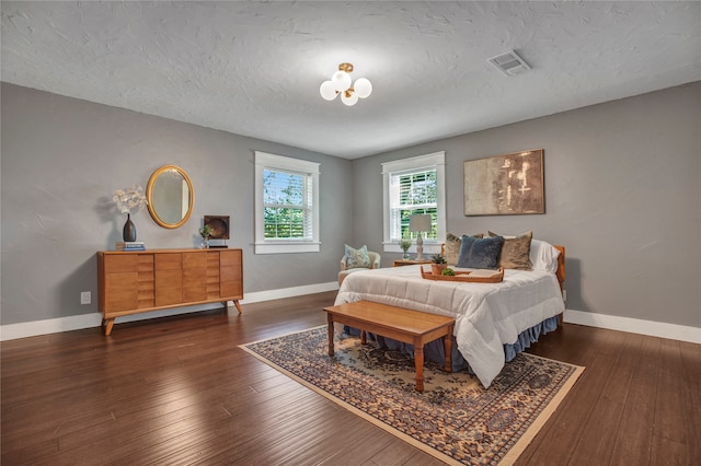 bedroom featuring visible vents, baseboards, a textured ceiling, and hardwood / wood-style floors