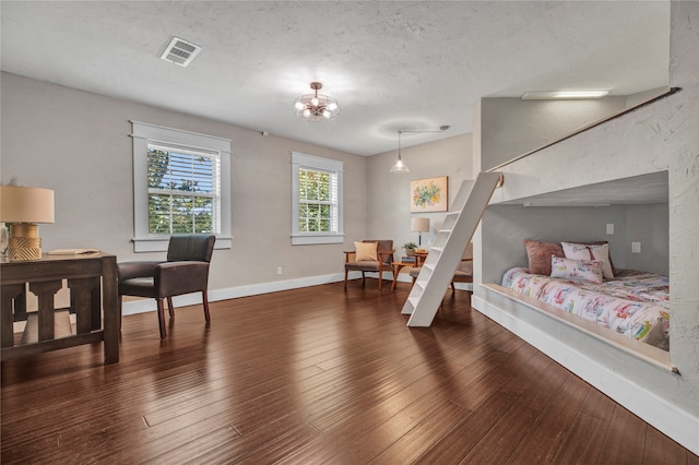 bedroom featuring visible vents, wood-type flooring, baseboards, and an inviting chandelier