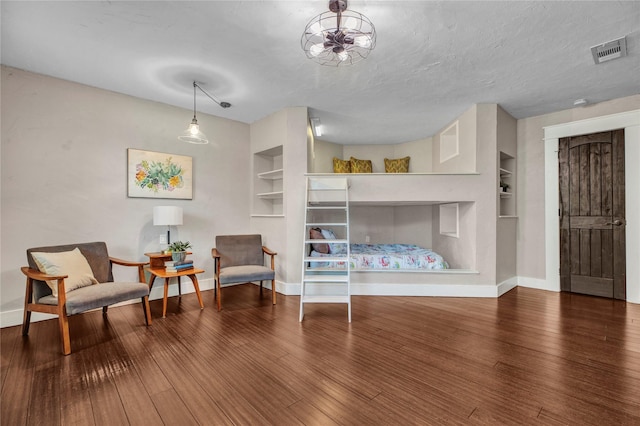 living area featuring built in shelves, wood finished floors, and visible vents