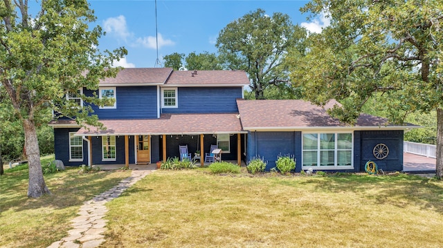 traditional-style home with a front yard, covered porch, and roof with shingles