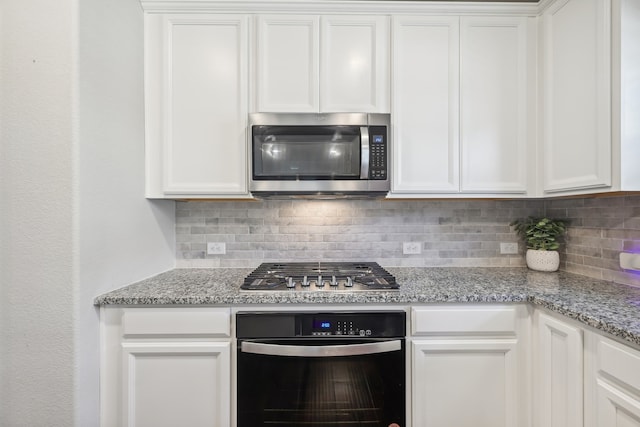 kitchen with appliances with stainless steel finishes, tasteful backsplash, white cabinetry, and light stone counters