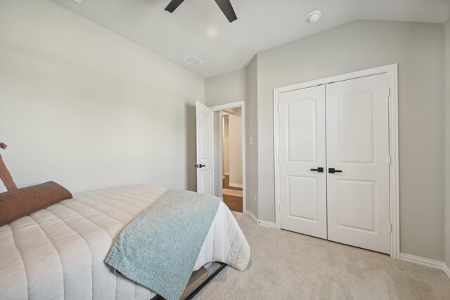 carpeted bedroom with ceiling fan, a closet, and vaulted ceiling