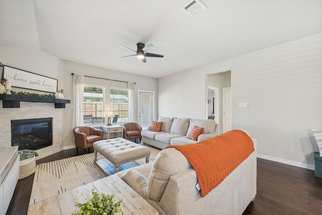 living room featuring ceiling fan, a fireplace, and dark wood-type flooring