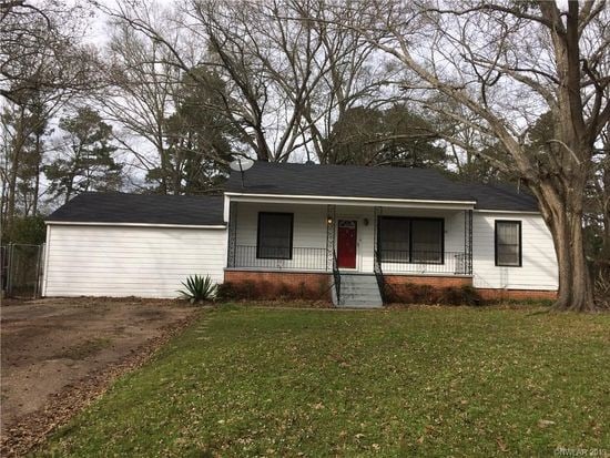 ranch-style house featuring covered porch and a front yard